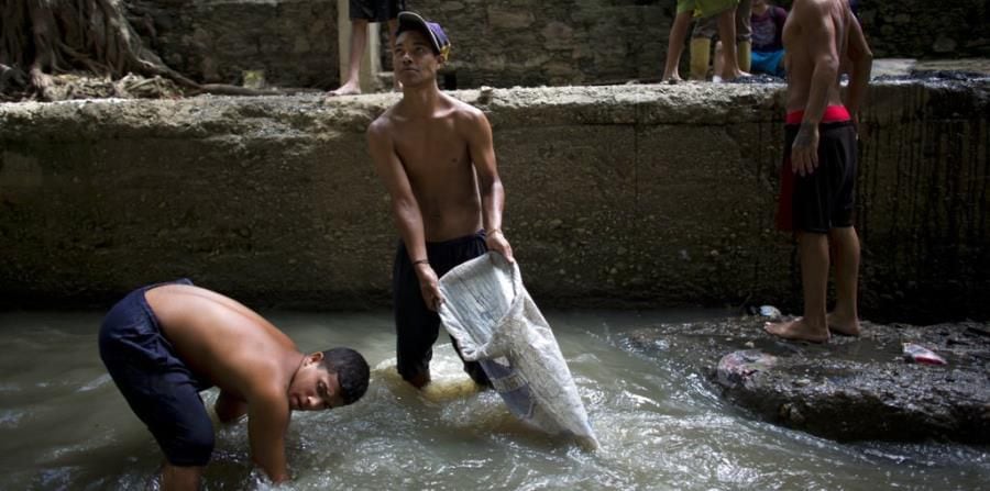 Venezolanos buscan el sustento en aguas de un rió contaminado